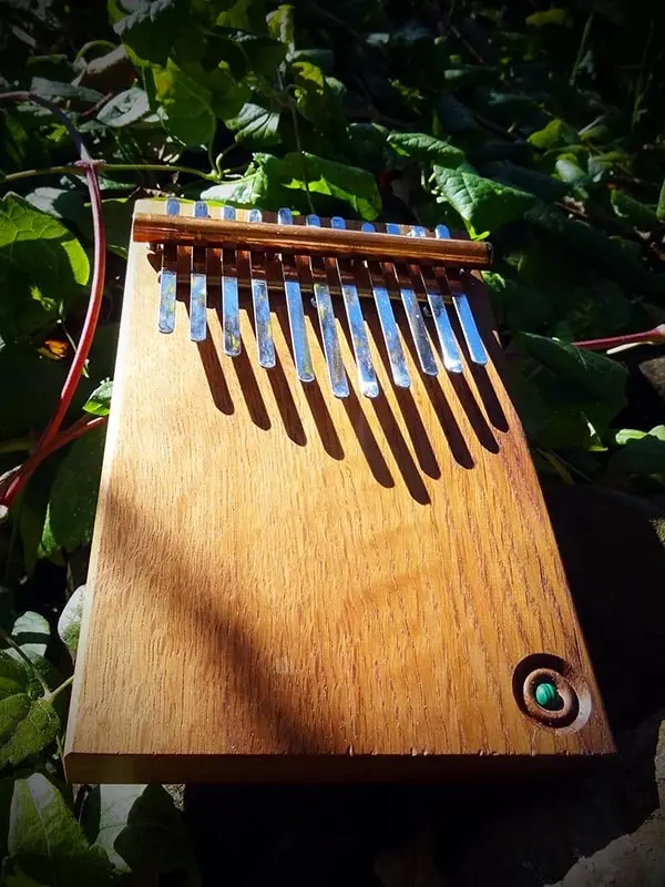 Kalimba 11 lames artisanale en bois fabriquée à la main dans l’Atelier La Goutte, un petit instrument mélodique au son doux et apaisant.
